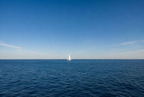 Einzelnes Segelboot unter weitem blauem Himmel